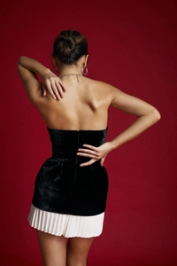 Rear view of sleek black velvet tube top with zipper detail and white pleated skirt