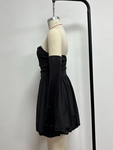 Detailansicht vom schwarzen trägerlosen Minikleid mit Falten und passenden Handschuhen