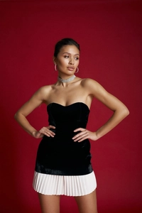 Detail of black velvet tube top and white pleated mini skirt with elegant silver jewelry