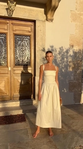 Detailed texture of cream satin dress with tie-up straps and elegant waist pleats
