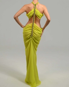 Detail of neon green chiffon dress featuring an open back and decorative metal chain strap