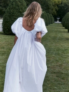 Vue détaillée d'une robe longue blanche à manches bouffantes et dos carré dans un jardin