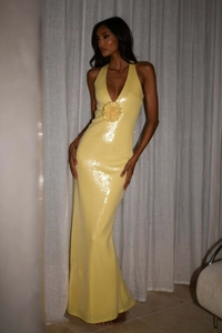 Detail of sequined yellow evening dress featuring a 3D floral accent and halter neckline