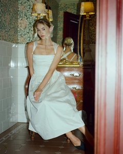 Detailed view of white satin dress featuring elegant pleated bodice and square neckline
