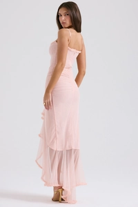 Détail d'une robe en maille rose clair avec ourlet asymétrique à volants et plis fins