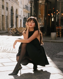 Petite robe noire chic avec dos nu et licou portée avec des talons aiguilles