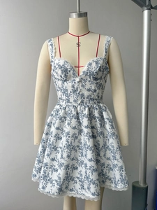 Détail de mini robe fleurie bleue avec boutons col en V et ourlet en dentelle blanche