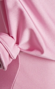 Gros plan macro sur le tissu satiné rose clair avec des détails plissés et torsadés élégants