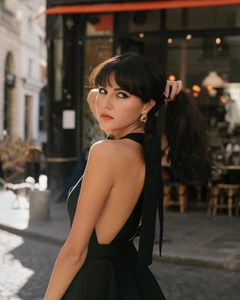 Close-up of elegant gold intertwined hoop earrings and black halter backless dress