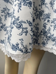 Détail de l'imprimé floral bleu avec bordure en dentelle blanche délicate sur l'ourlet