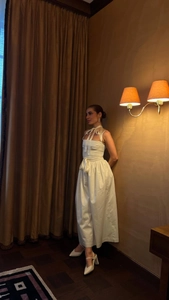 Detail of elegant white satin maxi dress featuring pleated bust and large bow tie accent