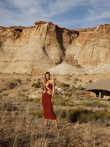 Detail of a red cutout bandage maxi dress with metal rings in a desert vacation setting