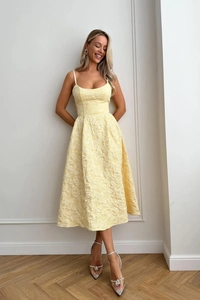 Gros plan sur l'élégante robe jaune pâle présentant une texture délicate en tissu jacquard