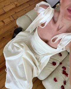 Detail of elegant off-shoulder ivory satin dress with pleated bust and ribbon straps