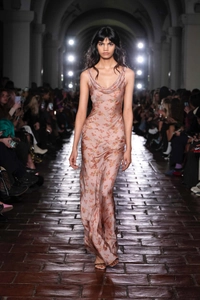 Detail of floral satin maxi dress featuring a cowl neck and silk-like texture on runway