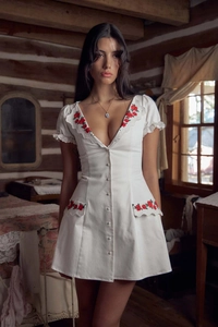 Close-up of red rose embroidery and delicate lace trim on a white V-neck dress