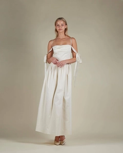 Detail of off-white satin dress showing elegant pleats and delicate ribbon ties on shoulders