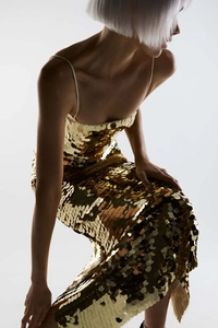 Macro shot of large golden sequins and delicate thin straps on a luxury party dress