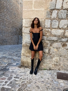 Chic robe courte noire sans manches avec taille ajustée et bottes hautes noires pointues
