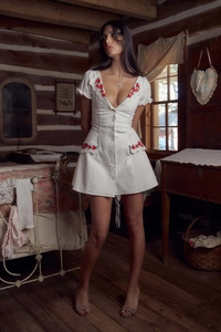 Close-up of white dress with red rose floral embroidery and delicate lace trim details