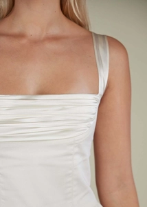 Detailed view of the square neckline and elegant ruched satin fabric on ivory dress