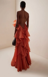 Detail of orange halter dress featuring layered ruffles and elegant backless cross-tie straps