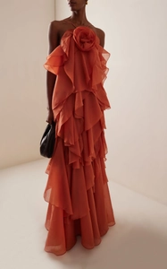 Detailed view of the 3D floral decoration and tiered ruffles on an orange halter maxi dress