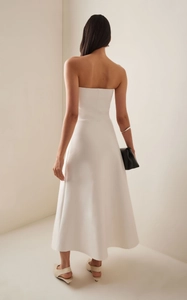Rear view of white strapless A-line midi dress showing elegant tailoring and draped hem