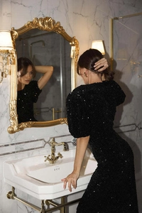 Dettaglio dell'elegante abito da sera nero con paillettes, maniche a sbuffo e taglio aderente