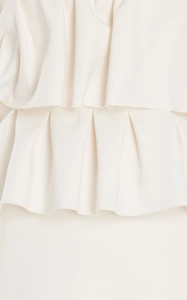 Detailed close-up of fine pleats and ruffled layers on a white formal maxi dress