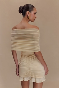 Detail of light yellow ruched mesh dress showing textured fabric and ruffle hem