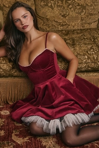 Detailed view of burgundy velvet dress with white lace trim and layered mesh hem