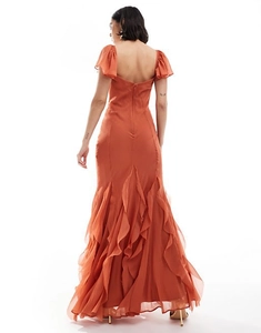 Detail of rust-colored maxi dress featuring ruffled hem, fish-tail silhouette and open back