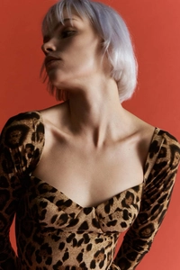 Detalle de escote corazón y vestido de leopardo de manga larga sobre fondo naranja