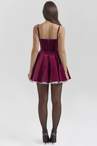 Detail view of the back of a burgundy velvet mini dress with hidden zipper and lace hem
