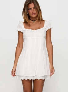Detailed close-up of white lace embroidery and eyelet texture on the mini dress