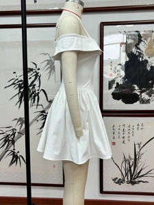 Detail of white off-the-shoulder mini dress with pleated hem and spaghetti straps