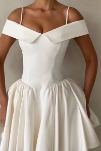 Detail of off-shoulder neckline and thin straps on a white satin pleated dress