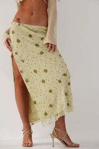 Detail of light green sequined maxi skirt featuring floral embroidery and a high side slit