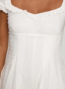 Close-up of elegant eyelet lace trim and Swiss dot fabric on a white summer dress