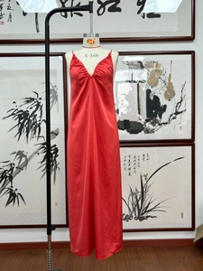 Détail de la robe rouge satinée avec col en V montrant les plis et la texture du tissu soyeux