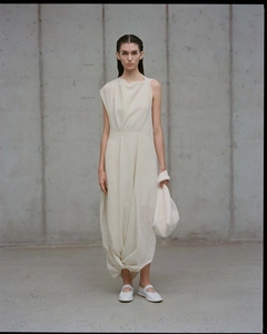 Detail of the unique knot design and draped hem on a cream sleeveless maxi dress