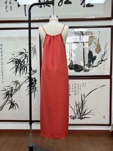 Détail de la texture en satin rouge et du col plissé sur cette robe longue fluide