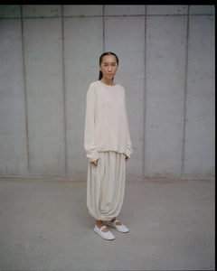 Detail of minimalist white knitted long sleeve top and beige lantern skirt on a model