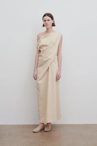 Detail of elegant beige one-shoulder dress with asymmetrical draped fabric and pleats