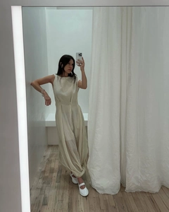 Detail of elegant beige sleeveless maxi dress with knot design and lantern pleated hemline