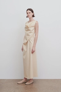Detail of elegant beige sleeveless dress featuring asymmetrical waist pleats and soft drape