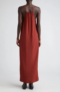 Vue de dos de cette robe longue rouge rouille avec de fines bretelles et des plis dos
