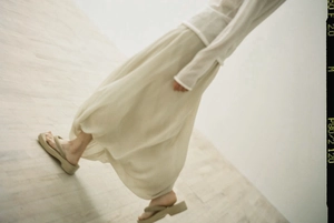 Detail of cream high-waisted pleated maxi dress with textured fabric and irregular knots