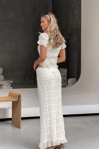 Detail of white smocked chiffon skirt set showing delicate ruffles and pleated texture